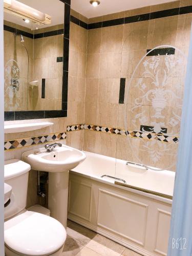 a bathroom with a sink and a toilet and a tub at The Brompton Hotel in London