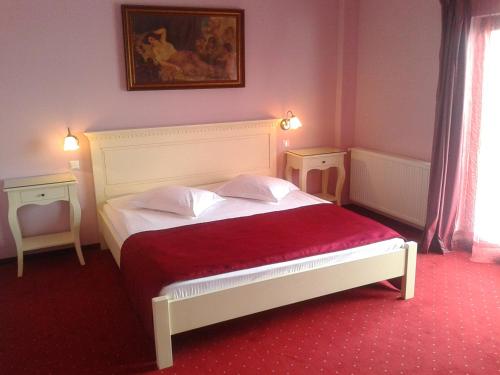 a bedroom with a white bed with a red blanket at Pensiunea Velvet in Iaşi