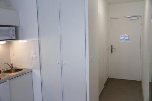 a white kitchen with a door and a sink at PARME ETAPE in Nice