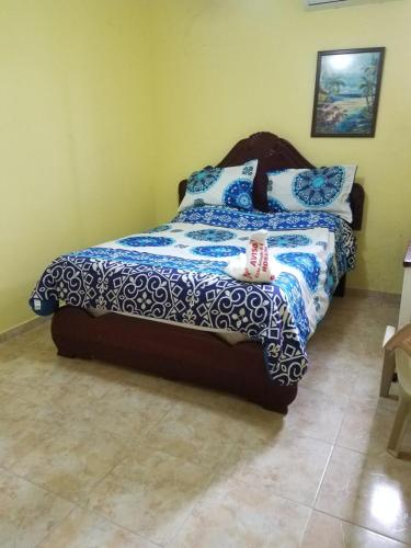 a bedroom with a bed with a blue and white comforter at Hotel Victoriano in San Felipe de Puerto Plata