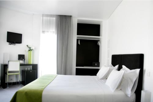 a bedroom with a white bed and a window at Benavente Vila Hotel in Benavente