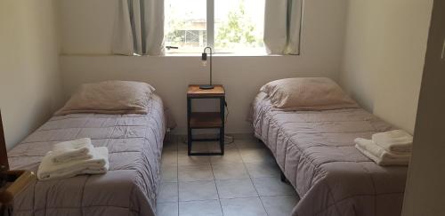 een kamer met 2 bedden en een tafel met een raam bij Torres del Centro - Av Colón esq Gral paz in Cordoba