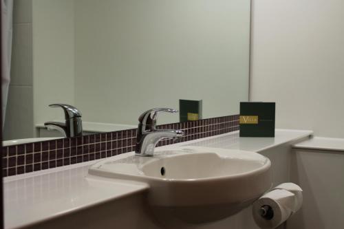 a bathroom sink with two faucets and a mirror at The Villa Express in Kirkham