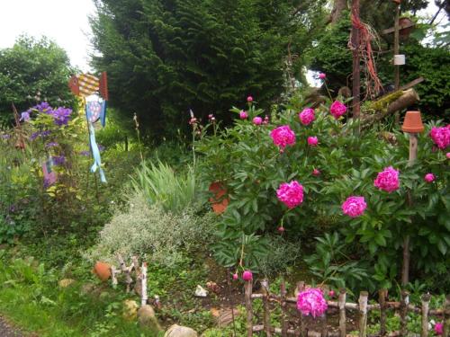 un giardino con fiori rosa e una recinzione in legno di Irgenbauer a Chieming