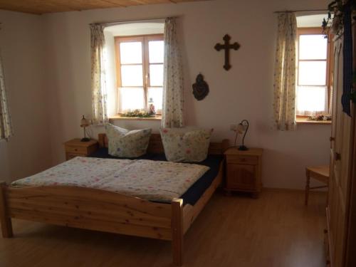 a bedroom with a bed and two windows and a cross at Irgenbauer in Chieming