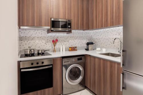 a kitchen with a washing machine and a microwave at Avani Plus Palm View Dubai Hotel & Suites in Dubai