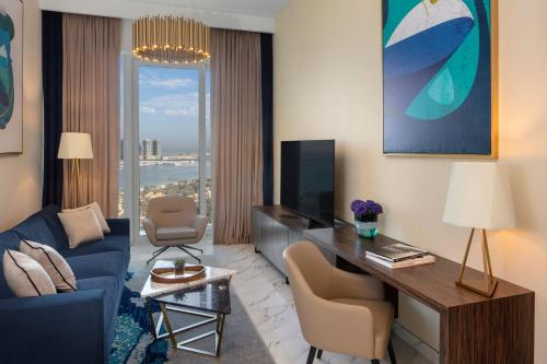 a living room with a blue couch and a tv at Avani Plus Palm View Dubai Hotel & Suites in Dubai