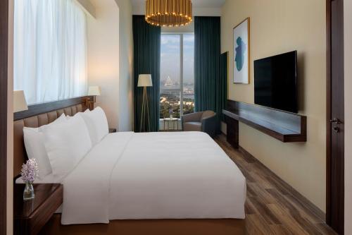a bedroom with a large white bed and a television at Avani Plus Palm View Dubai Hotel & Suites in Dubai