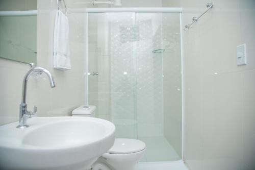 uma casa de banho com um chuveiro, um WC e um lavatório. em Hotel e Pousada Flor do Juá em Juazeiro do Norte