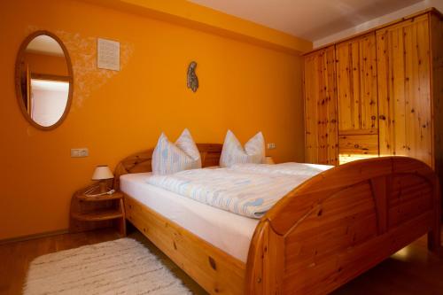 1 dormitorio con cama de madera y pared de color naranja en Naturlaub.pur, en Waldmünchen
