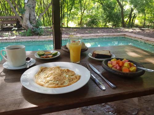 a table with a plate of food and a bowl of fruit at Le Campement in Bamako
