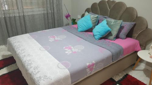a bed with blue and pink pillows on it at Apartman Sweet dreams 2 in Niš