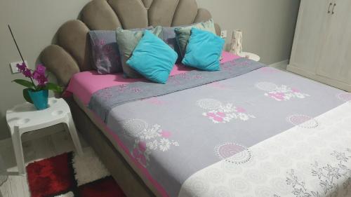a bed with pink and blue pillows on it at Apartman Sweet dreams 2 in Niš