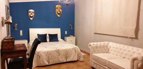 a bedroom with a bed and a couch and masks on the wall at Hotel Iris La Eliana in La Eliana