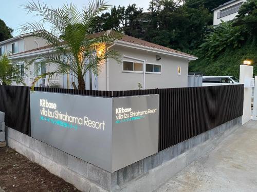 a fence in front of a house with a palm tree at KR バーズ ヴィラ伊豆白浜リゾート in Shimoda