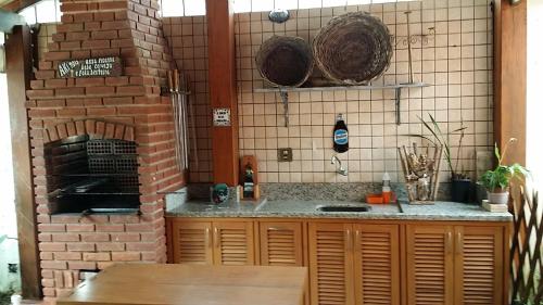 een keuken met een bakstenen oven en een aanrecht bij Residência Guarujá Praia Pernambuco Condomínio Fechado in Sao Paulo