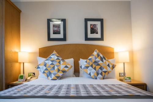 a bedroom with a bed with pillows and two lamps at Holiday Inn Manchester West by IHG in Manchester