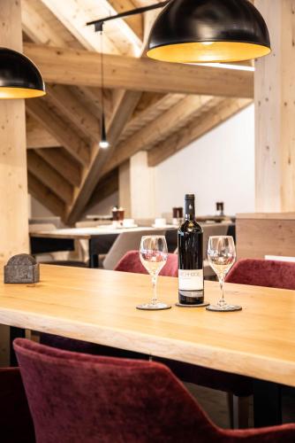 a bottle of wine sitting on a table with two wine glasses at Alpenhotel Schlüssel in Andermatt