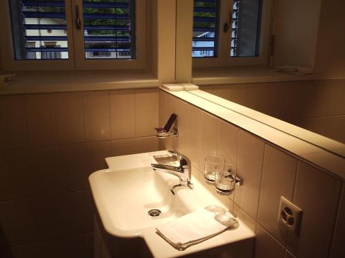 La salle de bains est pourvue d'un lavabo blanc et d'un miroir. dans l'établissement Hotel Albula & Julier, à Tiefencastel