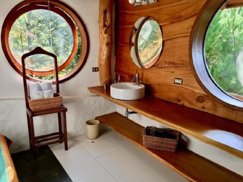 een badkamer met een wastafel en 2 ronde ramen bij Celestial Inn in Pucón