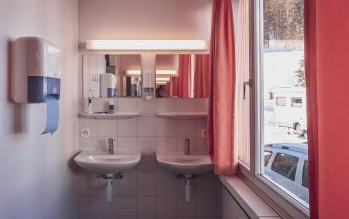 uma casa de banho com dois lavatórios em frente a uma janela em Maxon Pavillon by Mountain Hotels em Davos
