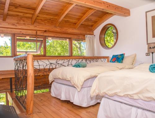 twee bedden in een kamer met houten plafonds en ramen bij Celestial Inn in Pucón