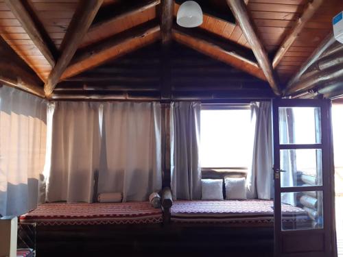 1 dormitorio con 1 cama y una ventana con cortinas en Cabaña de Montaña, La Casita Mina Clavero CBA en Mina Clavero