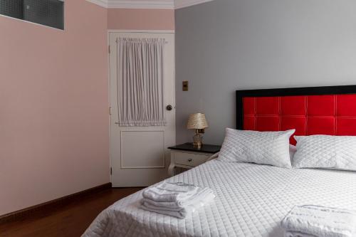 a bedroom with a red headboard and a white bed at Residencial Velia & Victoria in Cochabamba