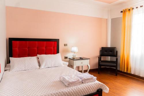 a bedroom with a bed with a red headboard and a chair at Residencial Velia & Victoria in Cochabamba