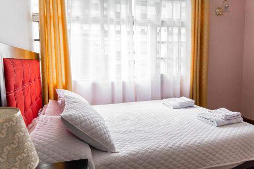 a bedroom with a white bed with a window at Residencial Velia & Victoria in Cochabamba