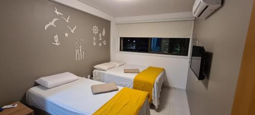 Cette chambre comprend 2 lits, une télévision et une fenêtre. dans l'établissement Apartamento Eco Life, à Porto de Galinhas