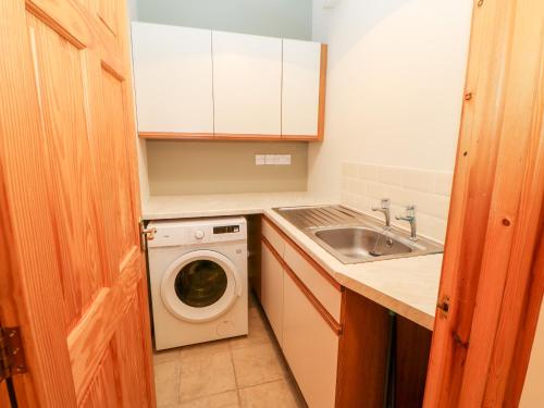 a kitchen with a washing machine and a sink at 2 Colby House Barn in Colby