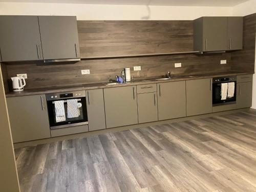 a kitchen with gray cabinets and a wooden floor at Fitters' accommodation near Dresden - comfortable beds, only men, free WLAN & parking spaces, also for trucks in Radeberg
