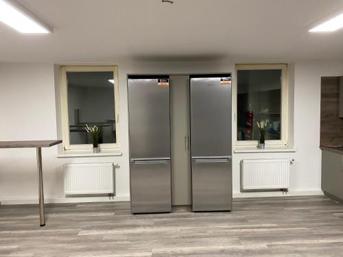 two metal refrigerators in a room with three windows at Fitters' accommodation near Dresden - comfortable beds, only men, free WLAN & parking spaces, also for trucks in Radeberg