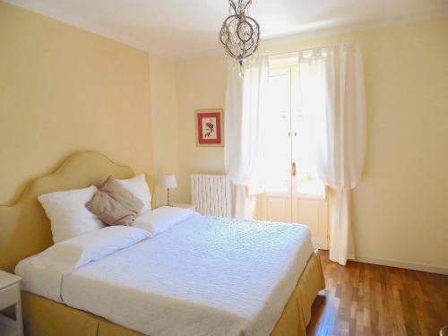 een slaapkamer met een bed met witte lakens en een raam bij Appartamento Porta Elisa in Lucca
