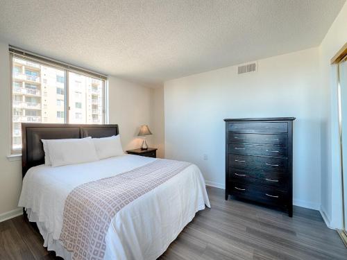 a bedroom with a bed with a dresser and a window at National at Courthouse Place in Arlington