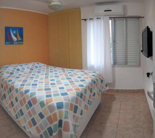 1 dormitorio con 1 cama con un edredón colorido en Brejatuba Residence! Conforto e lazer em excelente condomínio, en Guaratuba