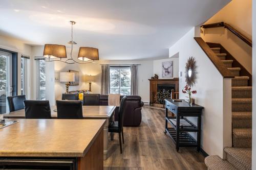 a living room and dining room with a stairway in a home at Aiglon by Rendez-Vous Mont-Tremblant in Mont-Tremblant