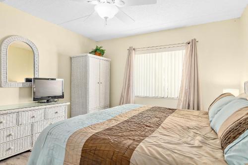 a bedroom with a bed and a tv and a window at Unit 2105 - Ocean & Racquet Resort in Saint Augustine Beach