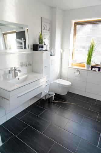 a white bathroom with a sink and a toilet at Ferienwohnung im Idyll 1 in Hengersberg