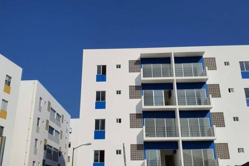 a white apartment building with blue windows at Loft 10 min from Oro &Holy Beach, Marina, Galerias in Puerto Vallarta