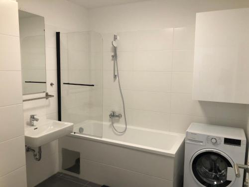 a bathroom with a shower and a sink and a washing machine at Neubau Wohnung Stadlau in Vienna