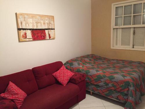 ein Wohnzimmer mit einer Couch und einem Bett in der Unterkunft Kitinete confortável frente ao mar in Santos