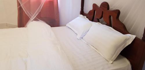 two beds with white pillows and a wooden headboard at Northern Pearl in Gulu