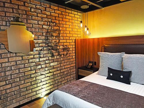 a bedroom with a brick wall and a bed at Cadillac Hotel Boutique in Mexico City