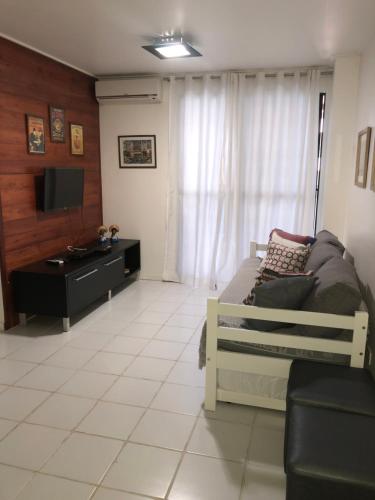 uma sala de estar com uma cama e uma televisão em Apartamentos Praia de Pajucara em Maceió