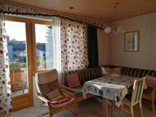 ein Wohnzimmer mit einem Tisch, Stühlen und einem Fenster in der Unterkunft Gästehaus Tropf in Litschau