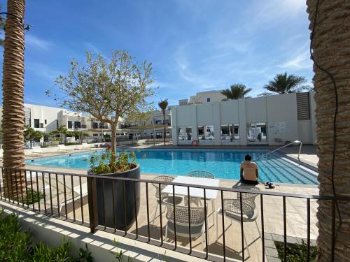 a man sitting on a chair next to a swimming pool at The White villa in Fujairah