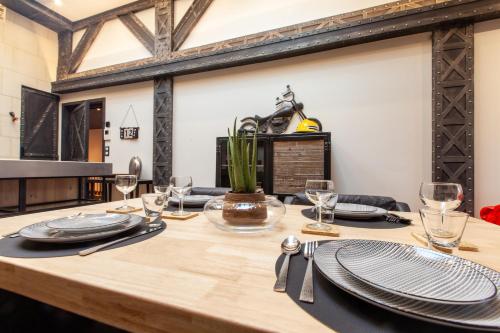 a wooden table with plates and glasses on top of it at OLuxuxy49 - Appartements T3 de prestige, Place du Ralliement, 2ème 3ème et 4ème étage SANS ASCENSEUR in Angers