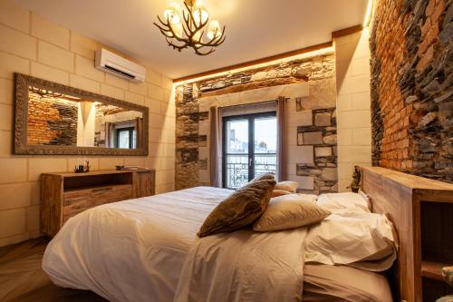 a bedroom with a large bed with a stone wall at OLuxuxy49 - Appartements T3 de prestige, Place du Ralliement, 2ème 3ème et 4ème étage SANS ASCENSEUR in Angers
